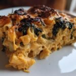 A close-up serving of the Creamy Butternut Squash Kale Alfredo Bake showing cheesy, orange sauce and dark green kale.