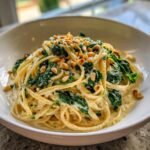 Close-up of Creamy Lemon Ricotta Pasta With Spinach Pine Nuts Delight in a white bowl.