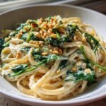 A close-up of Creamy Lemon Ricotta Pasta With Spinach Pine Nuts Delight tossed with linguine and topped with toasted pine nuts.