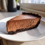 A thick slice of Decadent Chocolate Mousse Pie with a dark chocolate crust on a white plate.