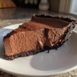 A thick slice of Decadent Chocolate Mousse Pie with a dark crust served on a white plate.
