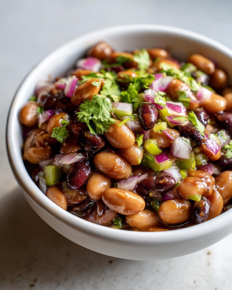 Close-up of a white bowl filled with Delicious Miso Sesame Dense Bean Salad, topped with red onion, green pepper, and cilantro.