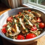Close-up of a Delicious Pesto Chicken Farro Bowl with sliced grilled chicken and cherry tomatoes.