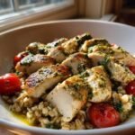 Close-up of a Delicious Pesto Chicken Farro Bowl featuring sliced chicken, farro, and cherry tomatoes.