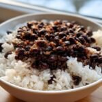 Close-up of a white bowl filled with white rice topped generously with seasoned black beans, showcasing the Delicious Rice And Beans A Cozy 30 Minute Recipe.
