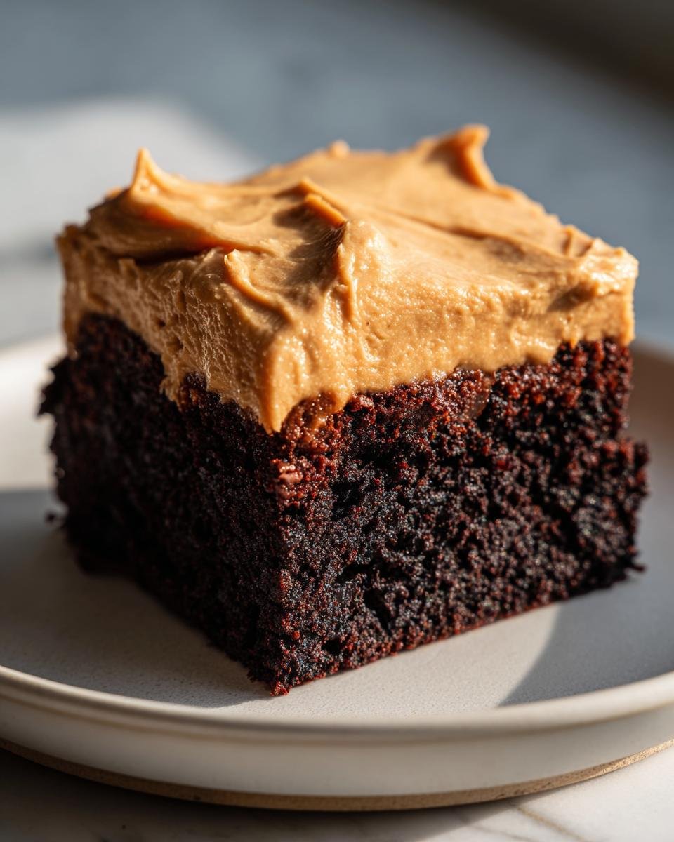 Close-up of a rich, dark chocolate slice of Irresistible Frosted Coffee Brownies topped with thick peanut butter frosting.