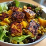 Close-up of a Grilled Charred Corn Haloumi Mango Salad Delight featuring grilled halloumi cheese, corn, and mango chunks over mixed greens.