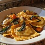 A close-up of Irresistible Butternut Squash Sage Ravioli topped with crispy sage leaves and browned butter.
