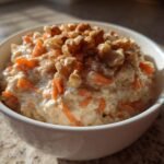 A white bowl filled with Irresistible Carrot Cake Overnight Oats topped with walnuts and cinnamon.