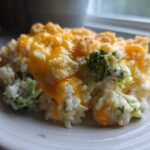 A close-up of a serving of Irresistible Cheesy Broccoli Rice Casserole topped with melted cheddar and crunchy breadcrumbs.