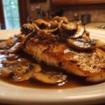 Close-up of a perfectly seared chicken breast smothered in rich brown sauce and sliced mushrooms from the Irresistible Chicken Marsala Recipe.
