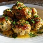 A stack of golden-brown Irresistible Chicken Piccata Meatballs garnished with fresh parsley in a lemon butter sauce.