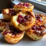 Close-up of golden baked Irresistible Cranberry Brie Bites topped with glossy cranberry preserves.