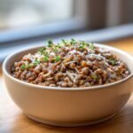 A close-up of a bowl filled with Irresistible Creamy Marry Me Lentils Recipe, topped with shaved Parmesan and fresh thyme.