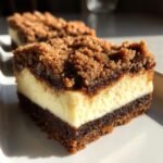 Close-up of an Irresistible Gingerbread Cheesecake Bars slice showing the dark gingerbread base, creamy filling, and crumb topping.