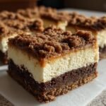 A close-up of an Irresistible Gingerbread Cheesecake Bars square showing the dark base, creamy filling, and crumb topping.