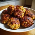 A plate piled high with freshly cooked, golden-brown Irresistible Greek Chicken Meat Balls.