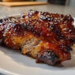 Two pieces of juicy turkey thighs coated in a thick, shiny, dark amber maple bourbon glaze.