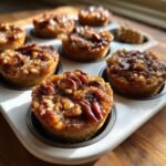 Close-up of freshly baked Irresistible Mini Pecan Pies cooling in a white muffin tin.