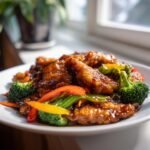 Close-up of Irresistible Potsticker Stir Fry featuring glazed potstickers mixed with bright broccoli and bell peppers.