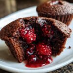 Close-up of an Irresistible Raspberry Chocolate Lava Cupcakes cut open, showing molten raspberry filling.