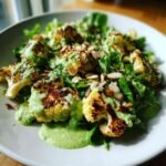 Close-up of Irresistible Roasted Cauliflower Green Goddess Salad topped with creamy green dressing and sliced almonds.