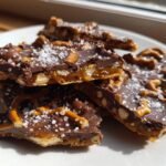 Close-up of broken pieces of Irresistible Salted Caramel Pretzel Bark topped with flaky sea salt.