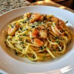 A close-up of Irresistible Shrimp Scampi Linguine topped with parsley and Parmesan cheese in a white bowl.