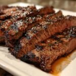 Close-up of juicy, sliced Irresistible Tender Grilled Marinated Flank Steak resting on a white platter.