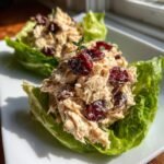 Two servings of leftover turkey salad mixed with dried cranberries, served in crisp lettuce cups.