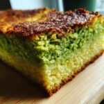 Close-up of a slice of Pistachio Gooey Butter Cake showing the vibrant green pistachio layer and golden crust.