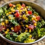 Close-up of a bowl filled with Refreshing Mexican Salad featuring lettuce, corn, black beans, tomatoes, and red onion.