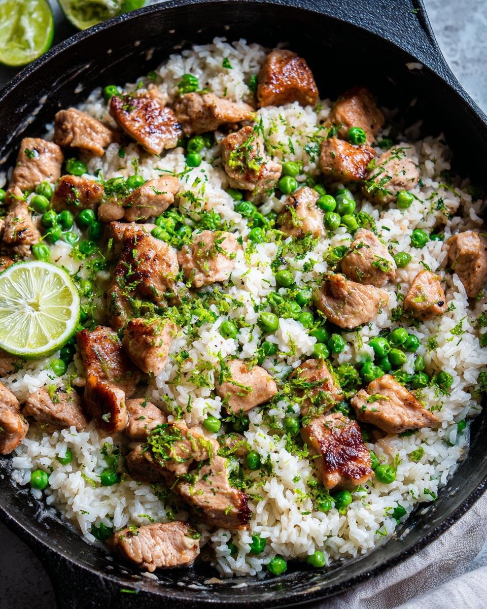 Close-up of Tropical Coconut Lime Chicken Rice Skillet with peas and lime zest in a black skillet.