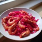 A white plate featuring cooked shrimp mixed with bright pink shredded vegetables, showcasing the Zesty 15 Minute Pickle Brine Shrimp Recipe Delight.